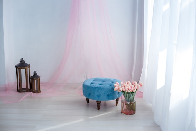 Luxuriöses, sauberes, helles weißes Interieur. ein geräumiges Zimmer mit Sonnenlicht und Blumen in Vasen, mit einem dekorativen Kamin, niedlichen rosa Plaids und einer Vase mit Marshmallows. Idee und Konzept eines Mädchenzimmers