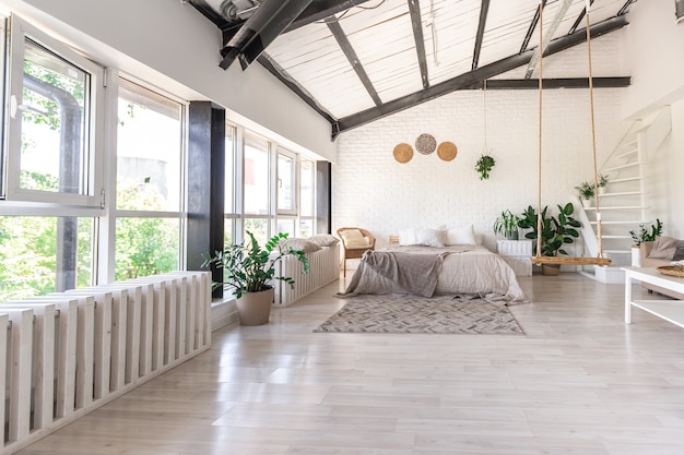 Luxuriöses Schlafzimmerdesign in einem rustikalen Cottage im minimalistischen Stil. weiße Wände, Panoramafenster, Holzdekorationselemente an der Decke, Seilschaukeln mitten in einem geräumigen Raum.