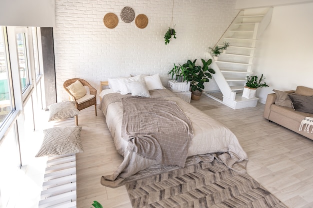 Luxuriöses Schlafzimmerdesign in einem rustikalen Cottage im minimalistischen Stil. weiße Wände, Panoramafenster, Holzdekorationselemente an der Decke, Seilschaukeln mitten in einem geräumigen Raum.