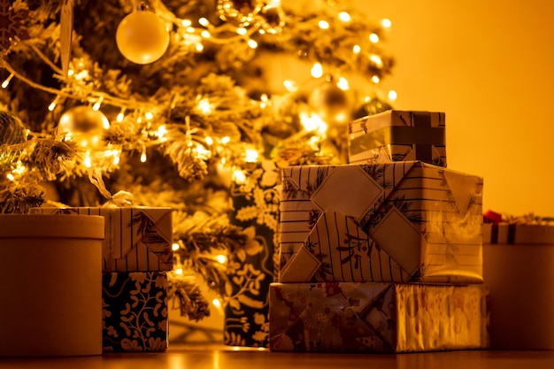 Luxus-Geschenkboxen unter dem Weihnachtsbaum auf dem Boden Gelbe warme Lichtgirlande Abend an Silvester 39 Weihnachten