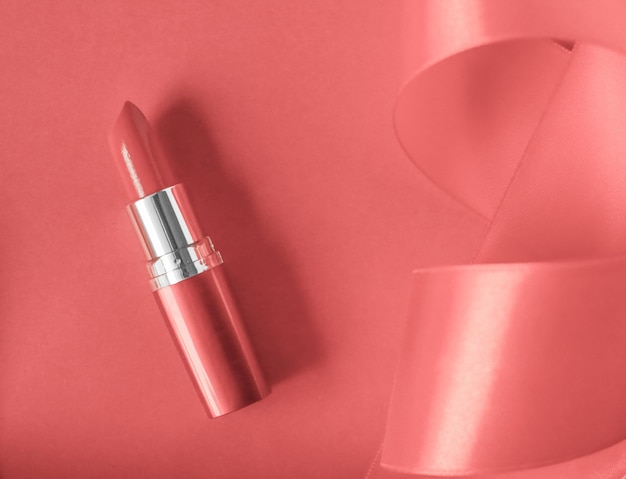 Luxus-Lippenstift und Seidenband auf korallenrotem Urlaubshintergrund Make-up und Kosmetik-Flatlay für Beauty-Marken-Produktdesign