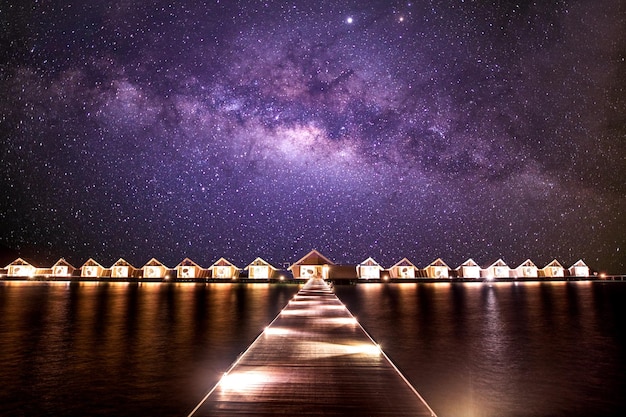 Luxus-Villen über dem Wasser, Pier-Bungalows, Meer, Strand bei Sonnenuntergang, atemberaubende Landschaft der Milchstraße