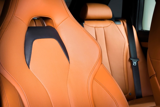 Luxusauto im Inneren Prestige modernes Auto Komfortable Ledersitze Orange rot perforiertes Leder Cockpit mit isoliertem schwarzem Hintergrund