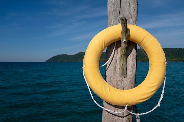 Luxusklassiker Safety Torus mit gelbem Tuch bedeckt. Er hängt an alten Holzpfählen, die sich auf dem Steg im Meer niederlassen