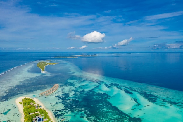 Luxusresortinsel auf den Malediven mit Wasservillen im Hintergrund und blauem Meer und Himmel, Luftbild