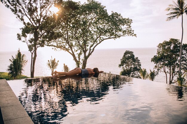 Luxusurlaubsreise zurück Ansicht der Frau, die im Unendlichkeitspool am Sommerstrandresort entspannt. Kaukasische Mädchen Tourist auf Wellness Spa Entspannung.