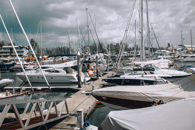 Luxusyachten und private Boote, die am Pier im Seehafen festgemacht sind. Im Hintergrund der leicht bewölkte Himmel