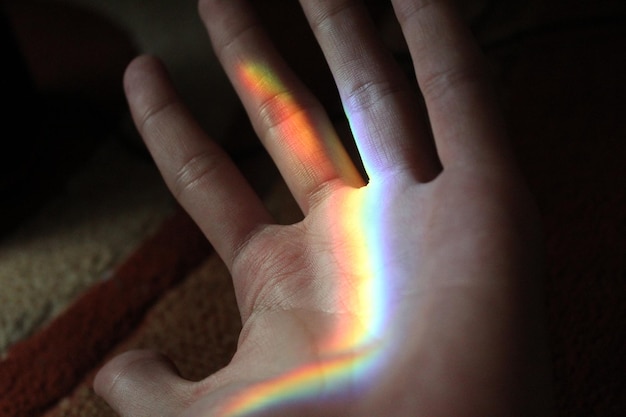 Foto una luz de arco iris se refleja en una mano.