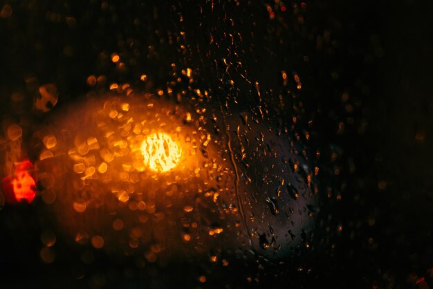 Foto la luz del automóvil borrosa por el vidrio húmedo gotas húmedas en el vidrio