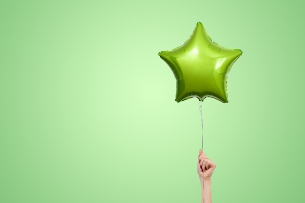 Foto luz - balão verde do aniversário próximo acima com espaço da cópia para o texto. estrela em forma de balão isolatd.