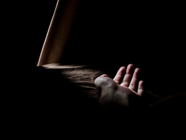 La luz cae en la mano recortada en el cuarto oscuro