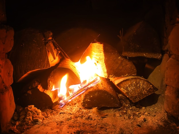 La luz cálida de un fuego brillante en una chimenea en la vieja estufa rusa. Fondo de llama y leña. Detalle de interior.