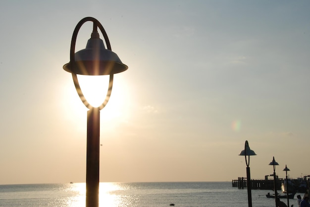 Foto luz de la calle en la playa contra el cielo durante la puesta de sol