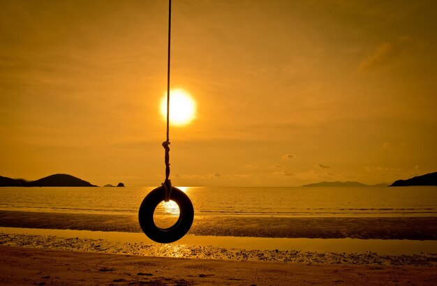 Foto luz de la calle en la playa de silueta contra el cielo durante la puesta de sol