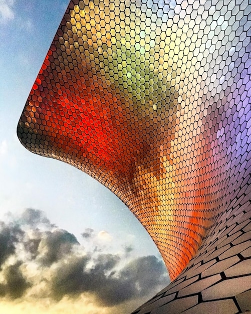 Luz de colores reflejada en la celosía del museo con nubes y cielo de fondo