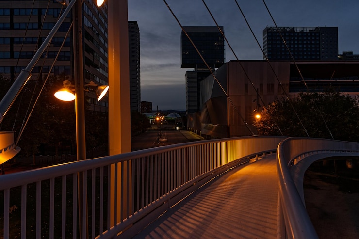 Foto luz de rua iluminada por uma ponte de pedestres contra edifícios à noite