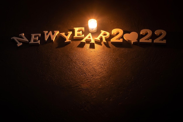 Luz de velas e fonte feliz ano novo 2022 fundo preto designcopy space