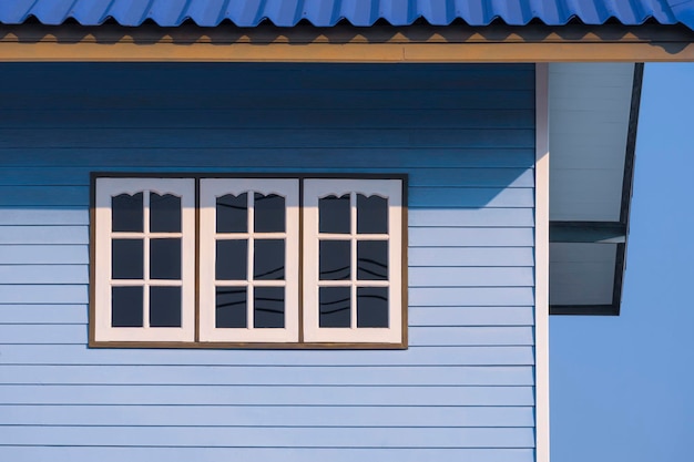 Luz do sol na superfície de 3 janelas brancas na parede de madeira azul da casa vintage