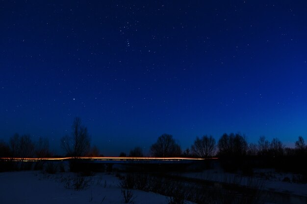 La luz de los faros de un coche sobre un fondo de cielo estrellado.