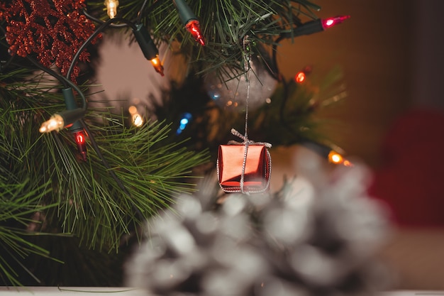 Luz de hadas y pequeña caja de regalo colgando en el árbol de navidad