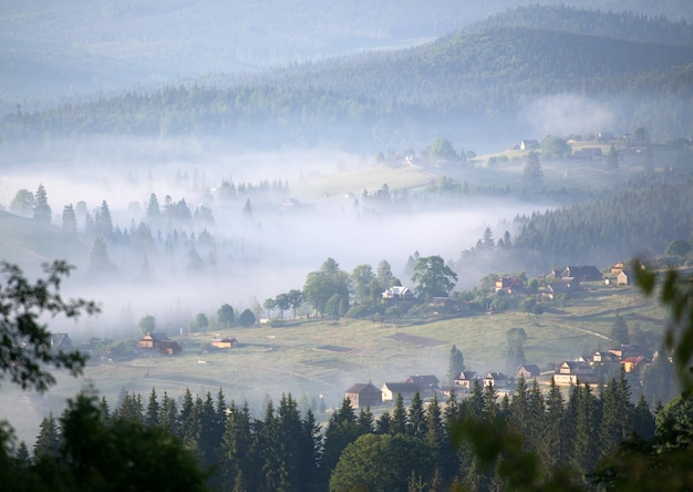 Una luz de la mañana en las montañas el pueblo se destaca en amarillo en la niebla