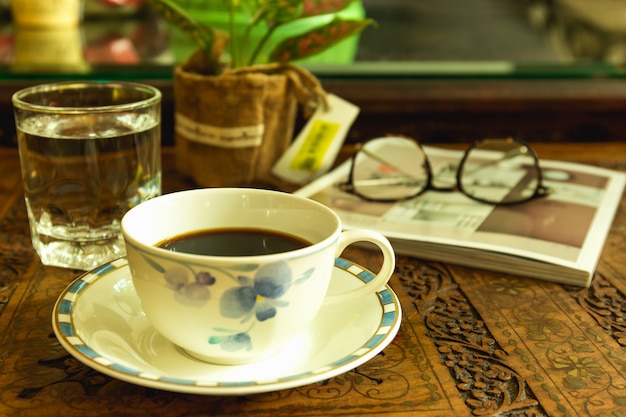 Luz de la mañana con taza de café y vaso de agua en talla de madera