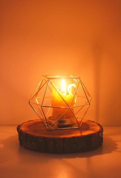 Luz quente de cera natural de abelha feita à mão em um suporte de vela em uma fatia de madeira