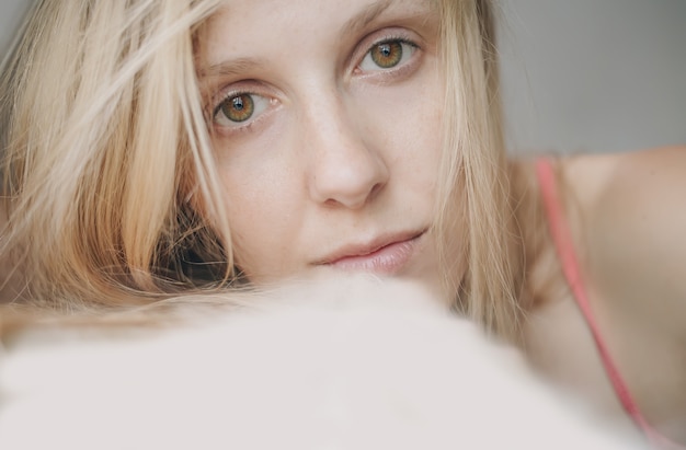 Luz retrato de mujer rubia triste o cansada con ojos verdes y marrones mirando a la cámara