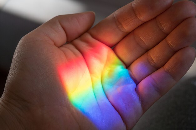 Luz del sol del arco iris en una mano