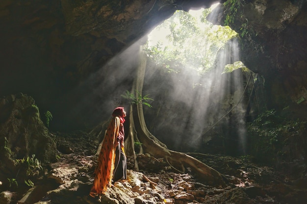 La luz del sol fluye sobre la mujer de pie en la cueva