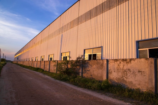 La luz del sol de la noche industrial se refleja en el almacén industrial contra la vista del paisaje del cielo azul