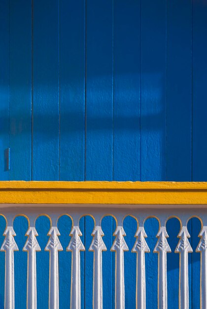 La luz del sol y la sombra en la superficie de la balaustrada blanca en la terraza con puerta de madera azul en estilo vintage
