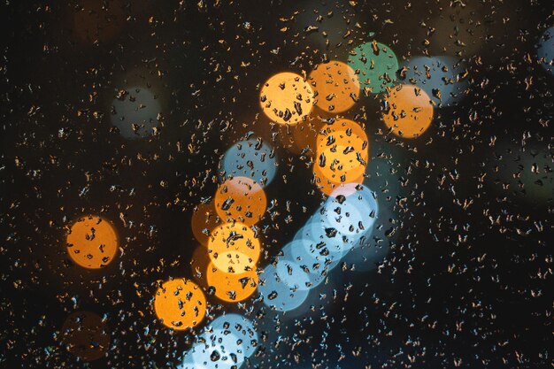 Foto luzes da cidade borrosas gotas de chuva no vidro da janela