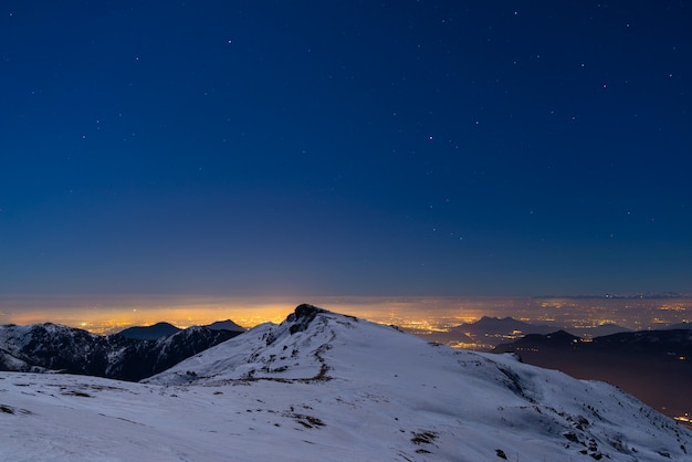 Luzes da cidade de Turin, opinião da noite dos cumes cobertos de neve pelo luar.