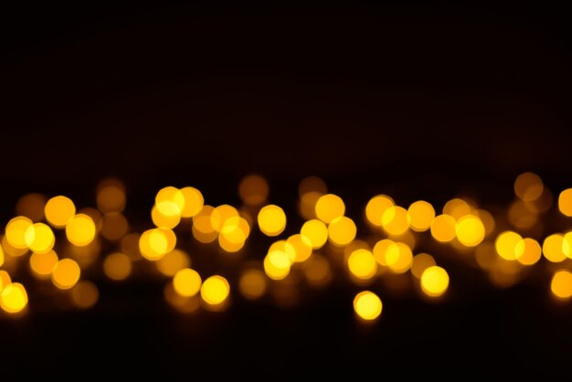 Luzes de bokeh de brilho dourado em fundo preto desfocado festa de feriado ou fundo de aniversário