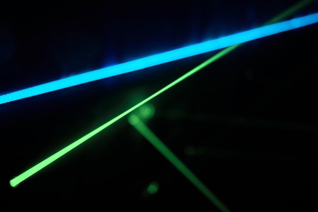 Luzes de laser de néon verdes brilhantes iluminam a escuridão criando linhas