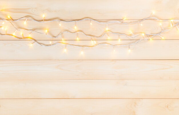 Foto luzes de natal em branco amarelo morno no fundo de madeira na celebração da véspera de natal