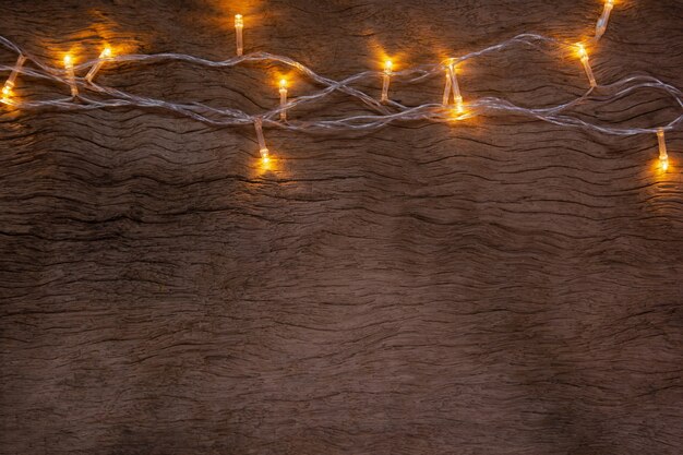 Foto luzes de natal em fundo de prancha de madeira. feliz natal e feliz ano novo com espaço de cópia para um texto.