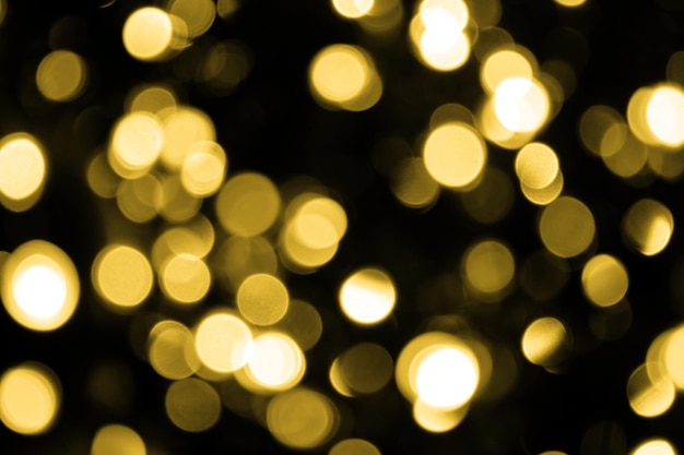 Luzes de ouro de natal bokeh desfocadas em fundo preto escuro Textura de brilho de ouro abstrato desfocado