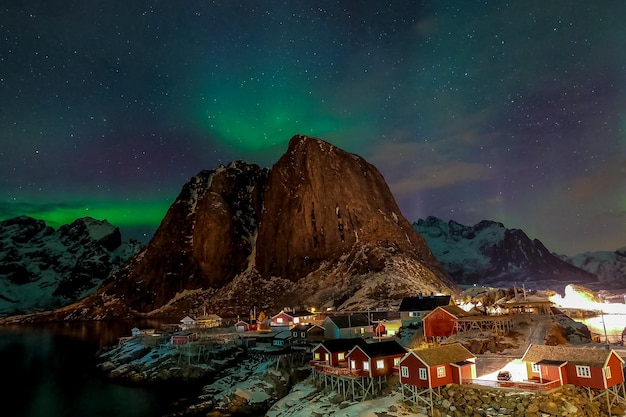 Luzes do norte sobre as montanhas e cabanas de pesca na vila de Hamnoy nas Ilhas Lofoten