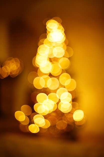 Luzes douradas brilhantes em forma de árvore de ano novo Fundo desfocado festivo