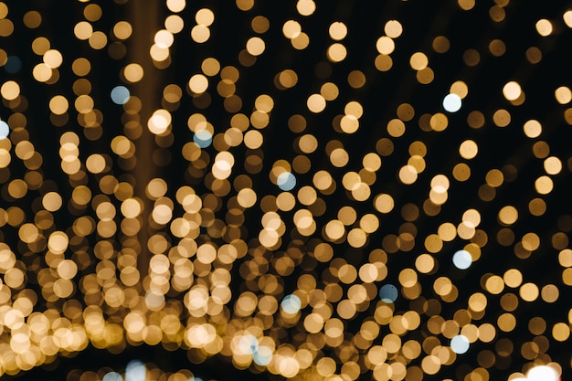 Luzes douradas de bokeh de Natal e Ano Novo borradas da cidade à noite Clima festivo Feriado de inverno