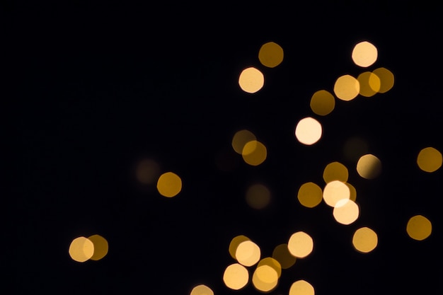 Luzes douradas do bokeh brilham. fundo preto festivo.