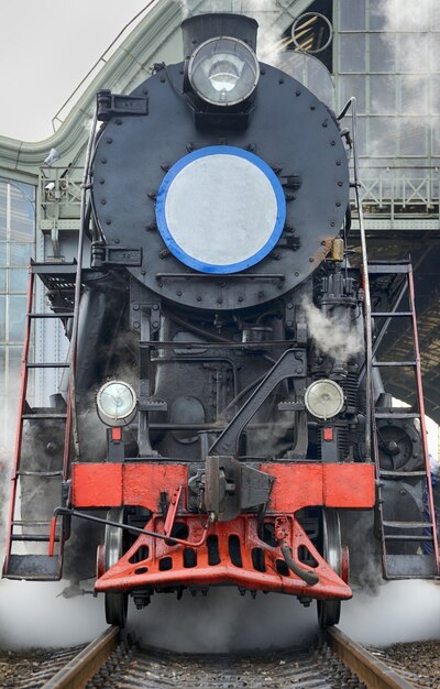 LVIV, UCRÂNIA - DEZEMBRO DE 2015: Antigo trem retro preto vintage soviético L-3535 na estação ferroviária em Lviv produz vapor dos canos