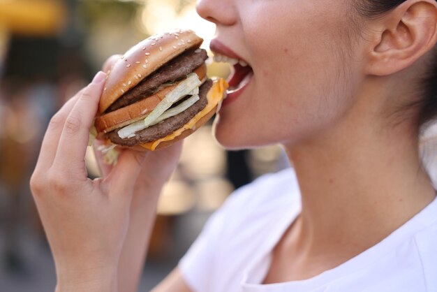Lviv, Ucrânia, 26 de setembro de 2023 Mulher comendo hambúrguer do McDonald's ao ar livre em close-up