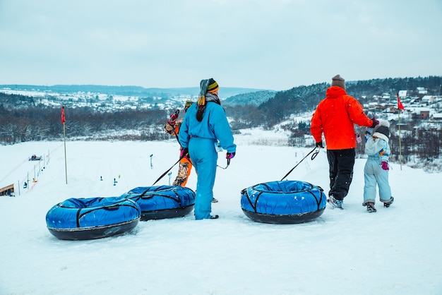 LVIV, Ucrania - 7 de enero de 2019: paseo familiar por la colina nevada con tubo de nieve. tiempo de invierno