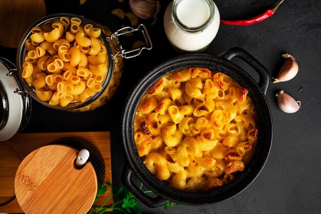 Mac und Käse, Makkaroni-Nudeln im amerikanischen Stil in Käsesauce auf dunklem Hintergrund. Foto in hoher Qualität