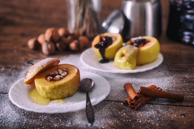 Maçã assada recheada com nozes, mel e chocolate em pratos de sobremesa branco, fundo escuro de madeira. Doce de natal. conceito de alimentação saudável.