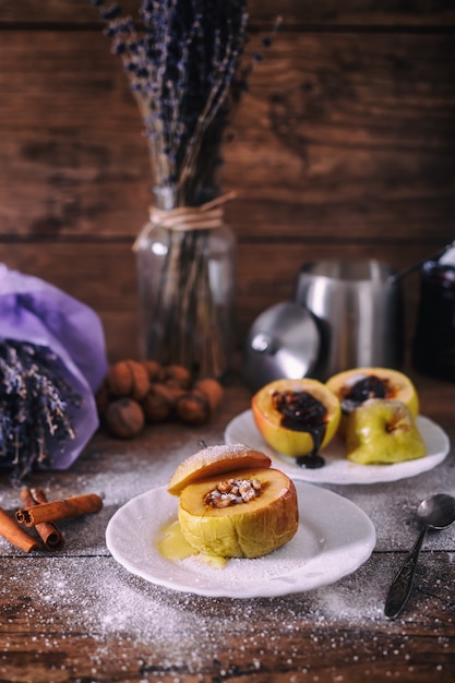 Maçã assada recheada com nozes, mel e chocolate em pratos de sobremesa branco, fundo escuro de madeira. Doce de natal. conceito de alimentação saudável.