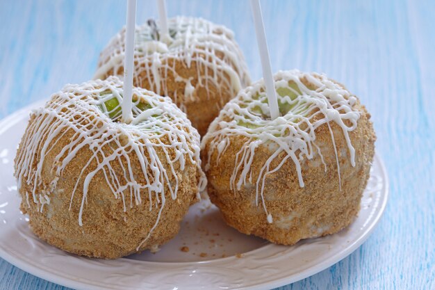 Foto maçã caramelo coberta com chocolate branco e migalhas de graham